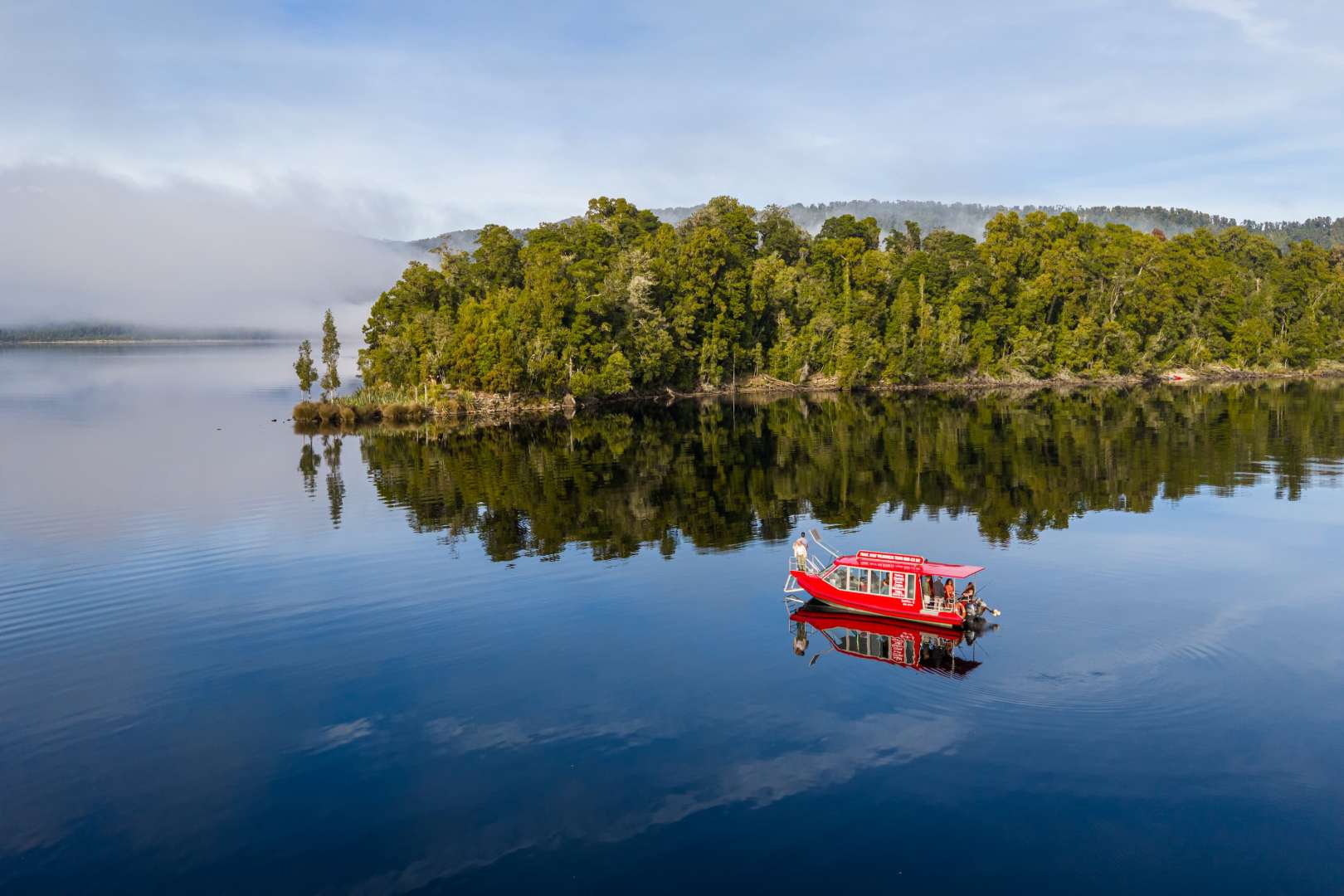 Cruise across pristine Lake Mapourika at Franz Josef