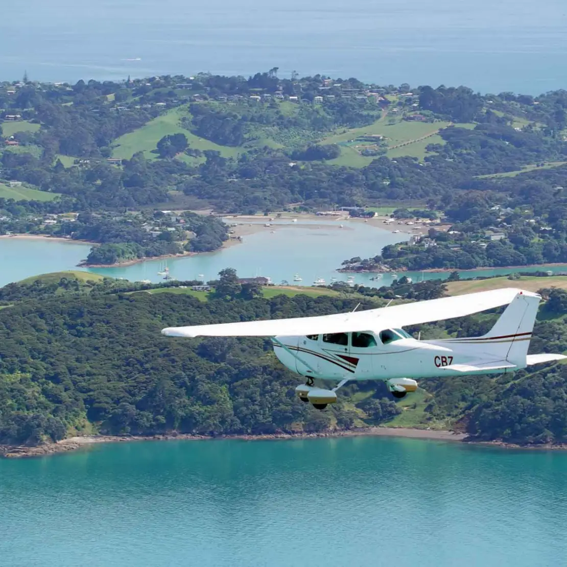 Scenic flight heading out over the majestic beach and quaint town of Oneroa